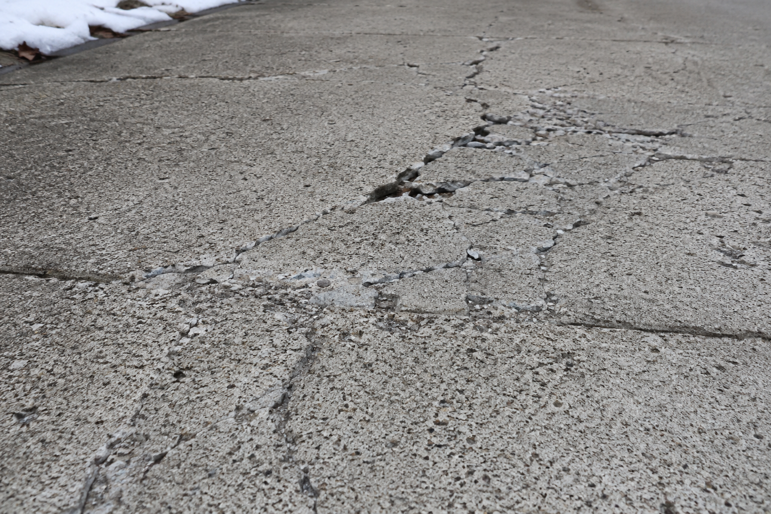 Close-up of freeze-thaw surface scaling and cracking on a concrete driveway slab in Missouri