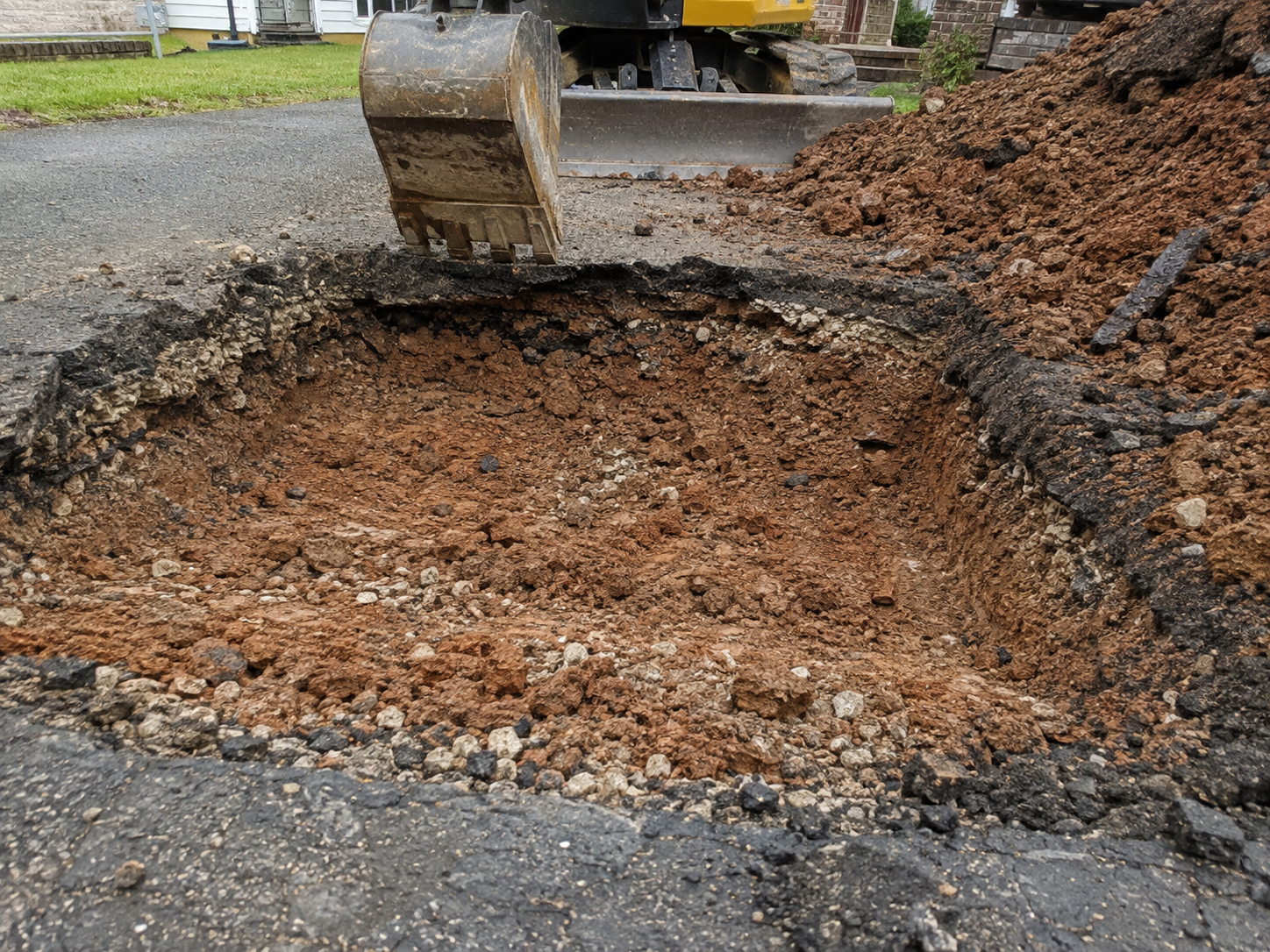 Excavated failed asphalt driveway showing thin base and clay subgrade dug out by a Springfield paving crew